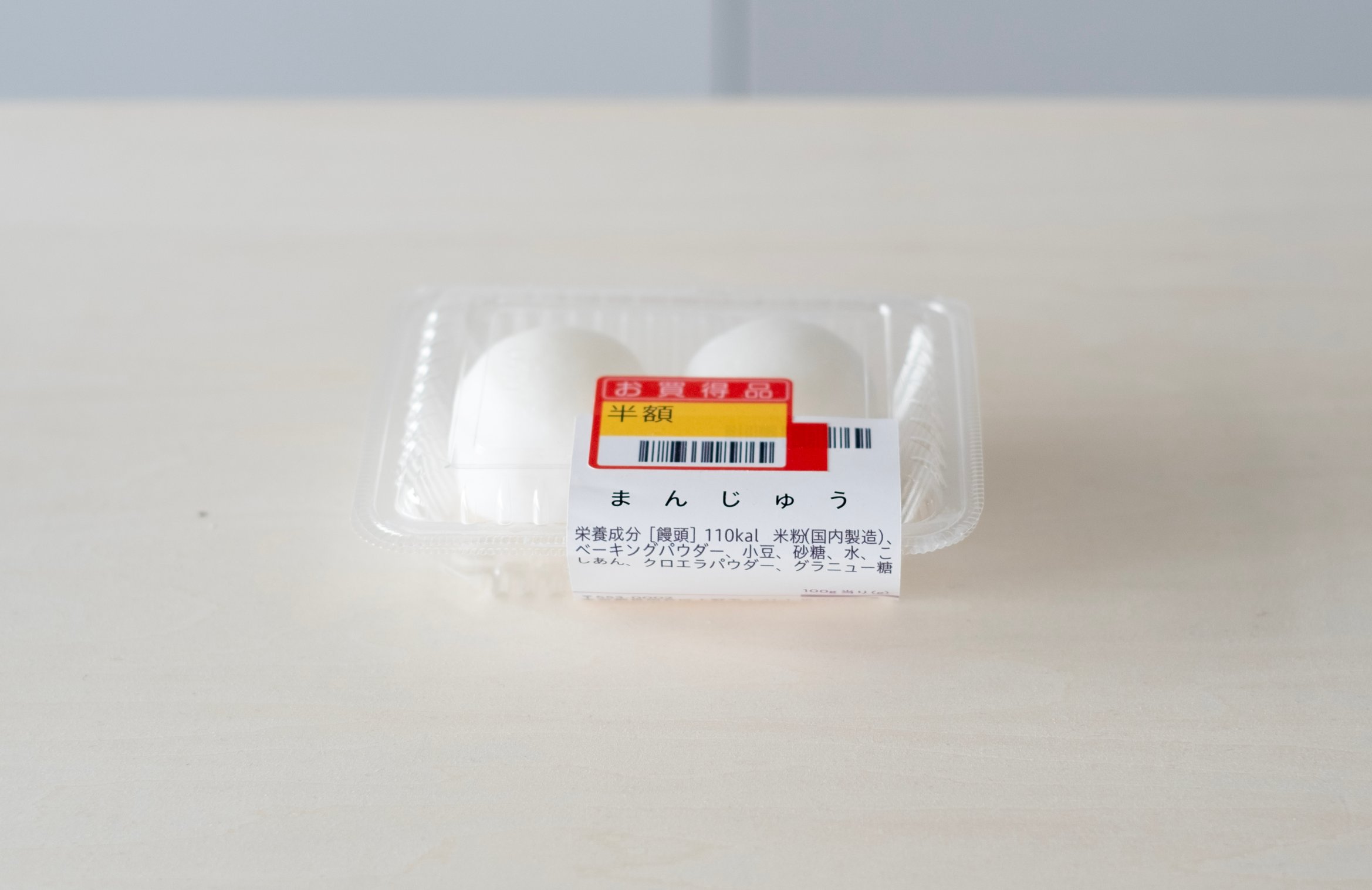 まんじゅうがフードパックに入れられている。半額シールが上から貼られている。