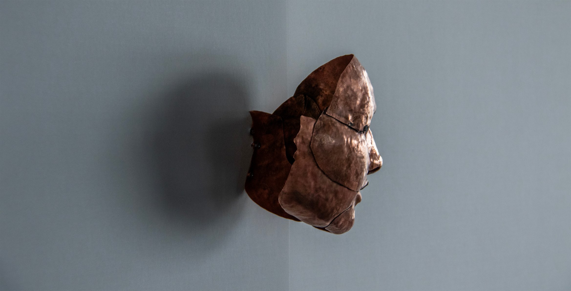 人の顔の形に彫刻された銅板。斜め後ろから見た写真。